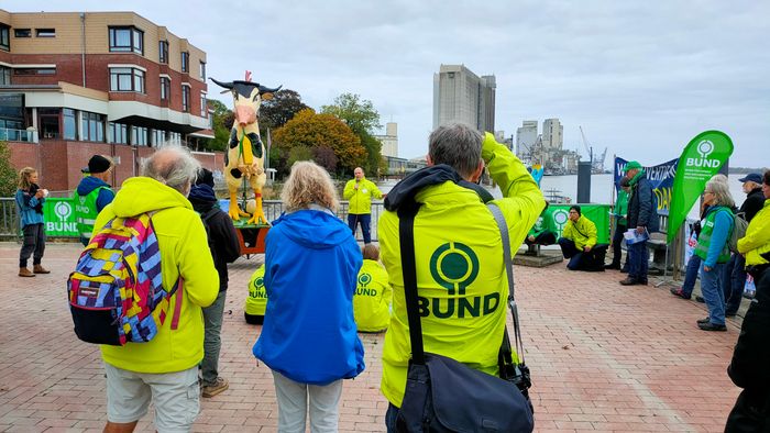 Aktive des BUND protestieren auf der Brake Kaje gegen Futtermittelimporte, industrielle Tierhaltung und die geplante Weservertiefung. Im Hintergrund ist ein Futtersilo zu sehen.